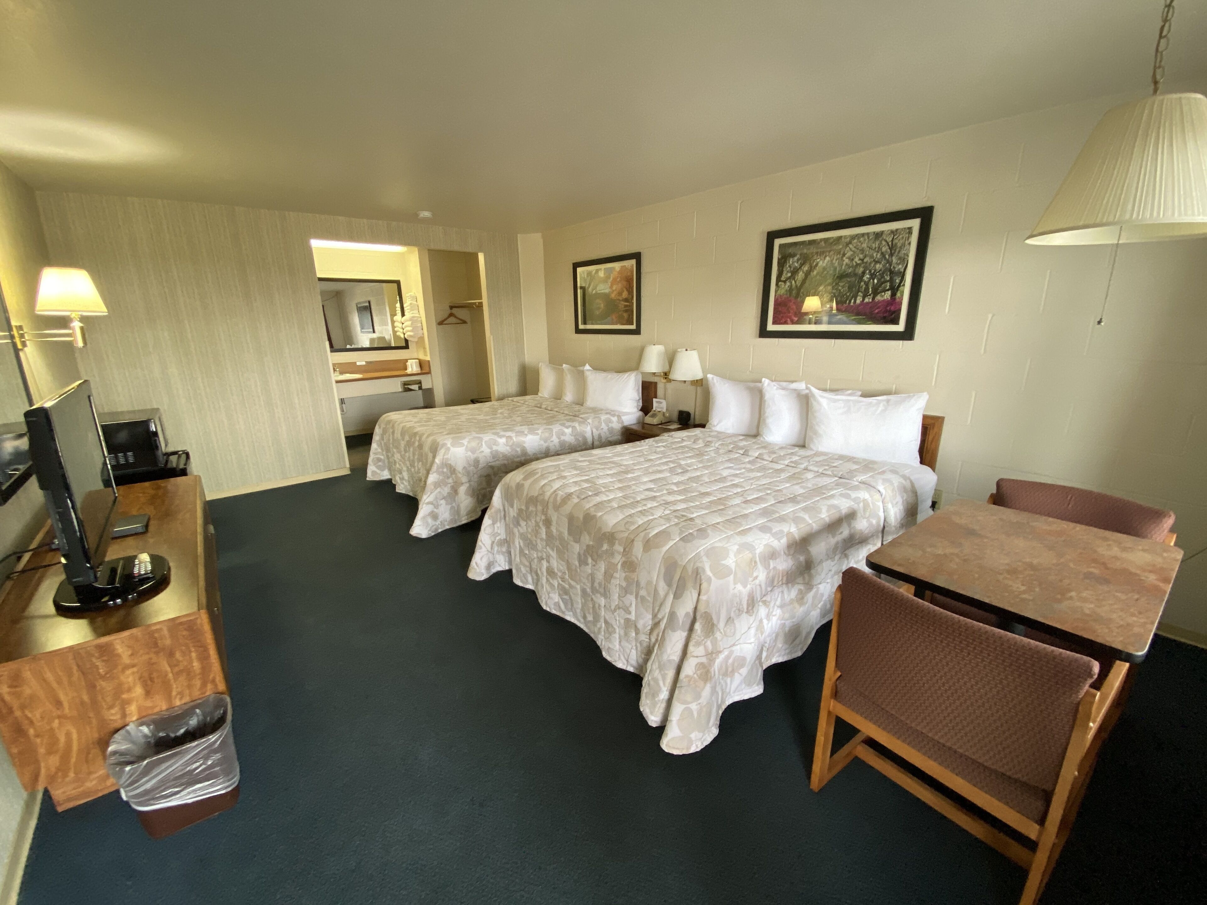 Een hotelkamer met twee bedden, een bureau met computer en telefoon, een stoel en een kleine prullenbak.