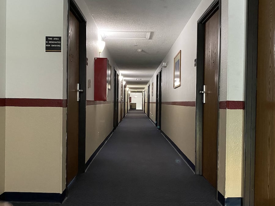 En lang, smal hotelskærs med døre på begge sider, et tæppe på gulvet, og et skilt der angiver et område for ikke-rygere.