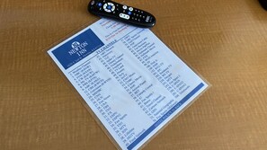 A TV channel guide with a remote control on top.