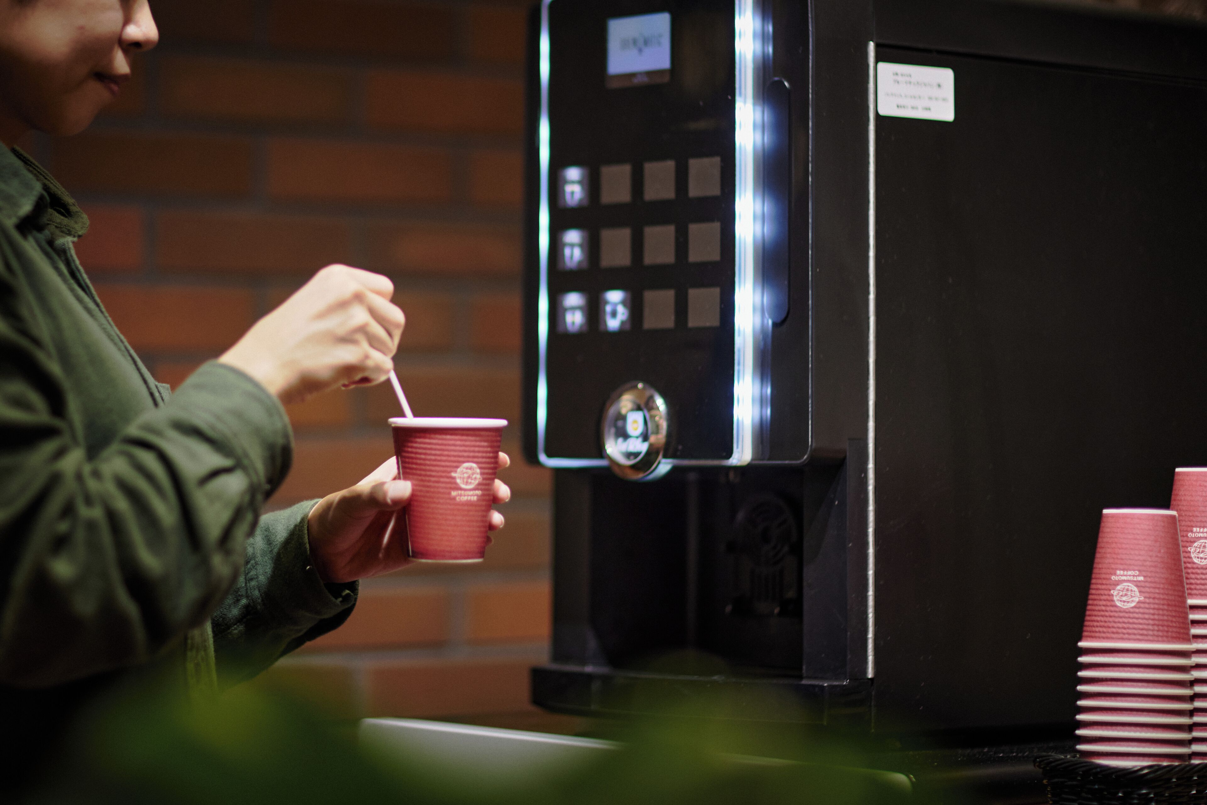 Eine Person hält eine rote Tasse in der Nähe einer Kaffeemaschine.