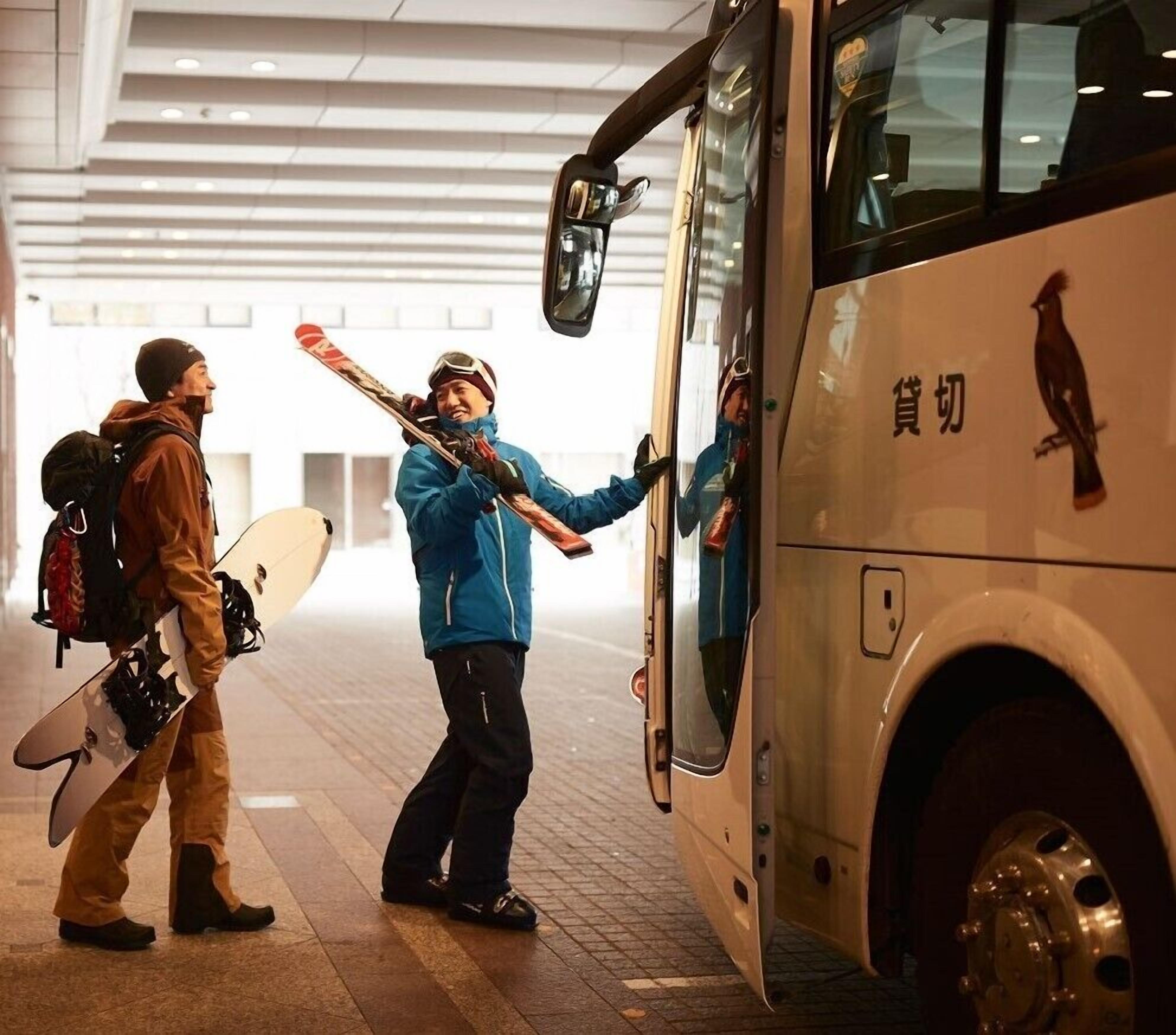 A bus with a bird decal and a person holding skis at the door.