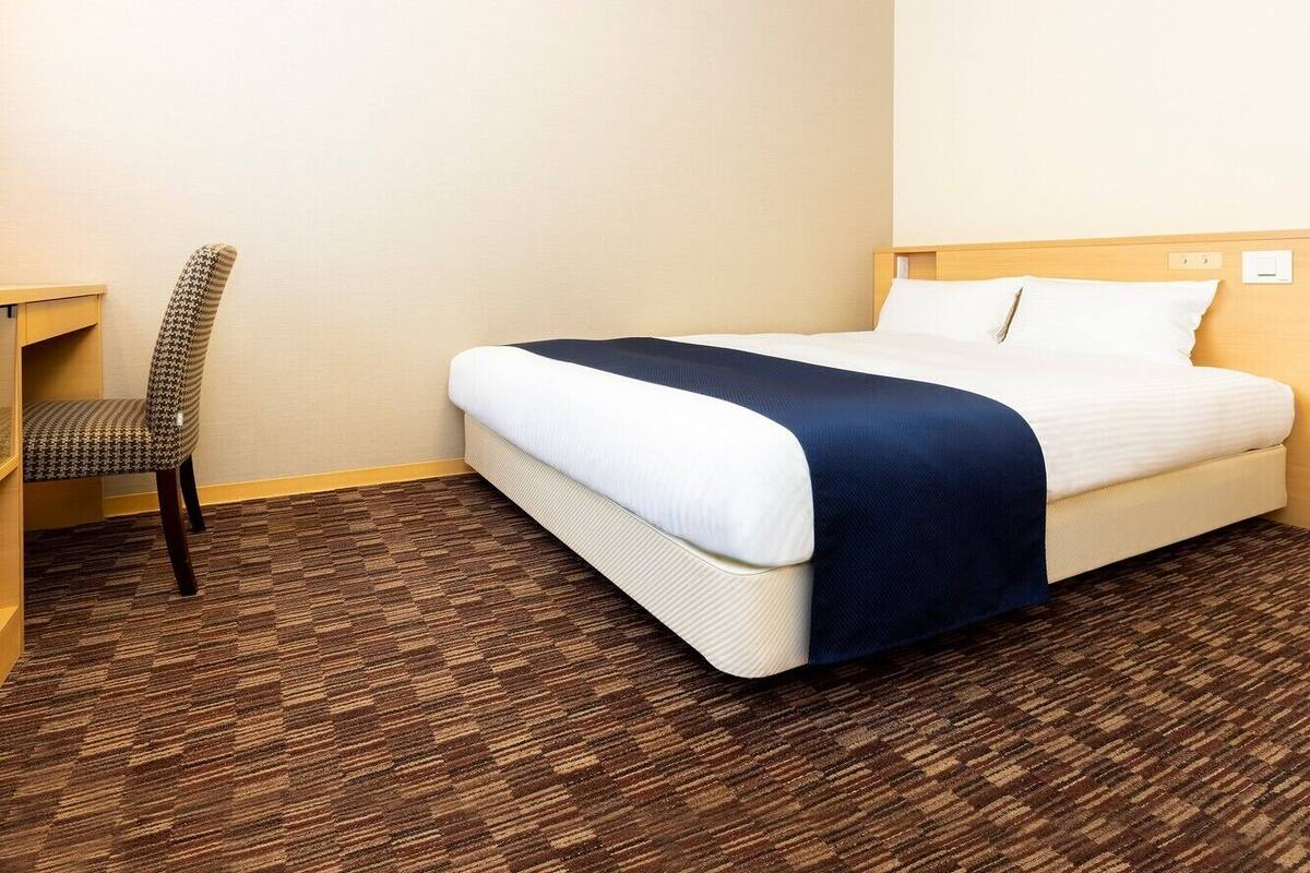 Une chambre d’hôtel avec un lit, une chaise et un bureau.