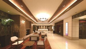 A spacious lobby with a central seating area, a reception desk, and a large chandelier. - Hotel WBF Grande Asahikawa (Asahikawa)