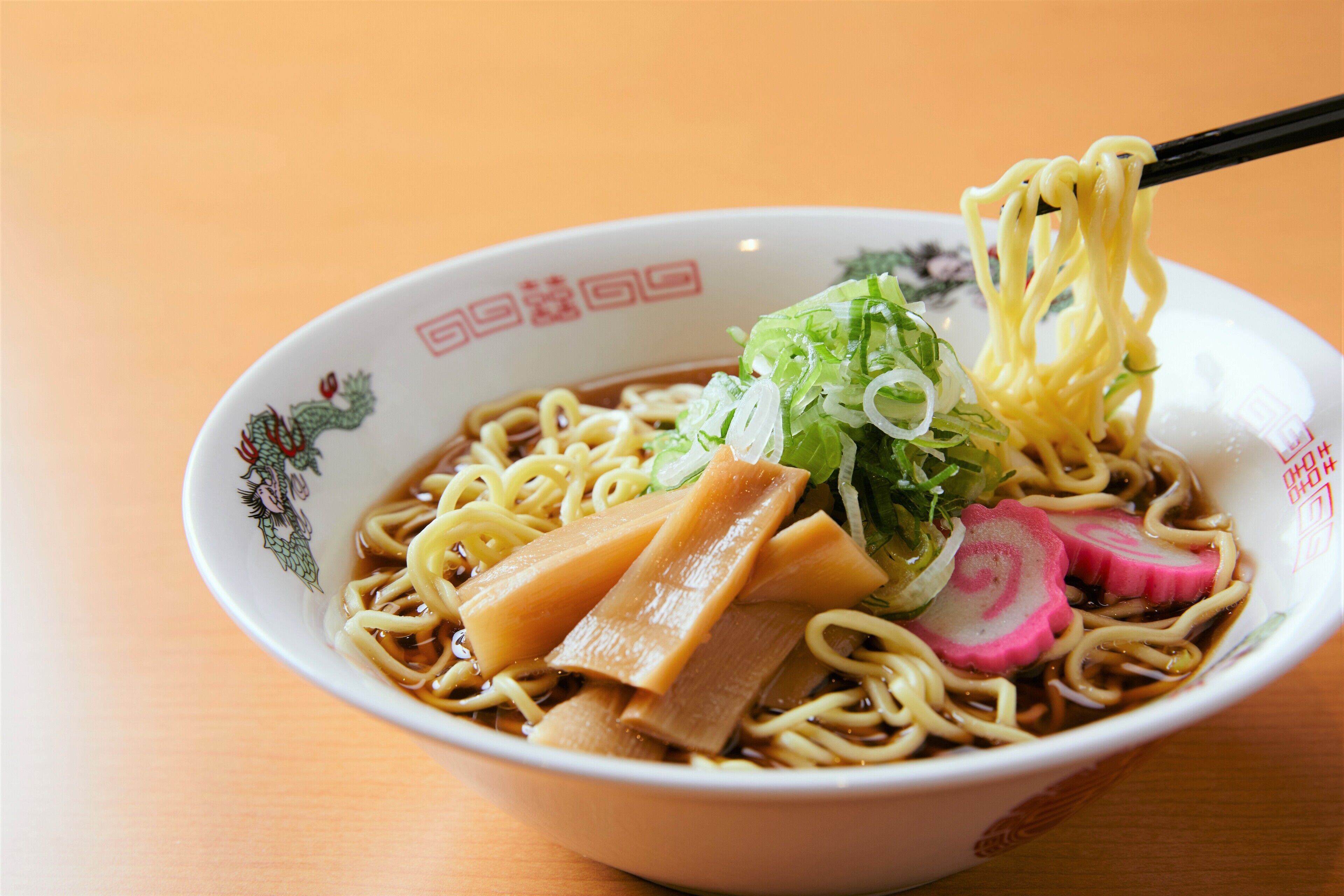 Un tazón de ramen con fideos, carne en rodajas y verduras.