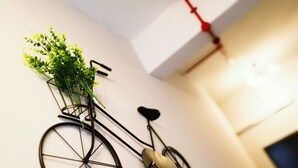 A wall-mounted bicycle with a plant in the basket. - Urban Hostel (Singapore)