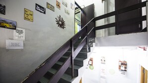 A staircase with a wooden handrail and a wall with various signs and notices. - Urban Hostel (Singapore)