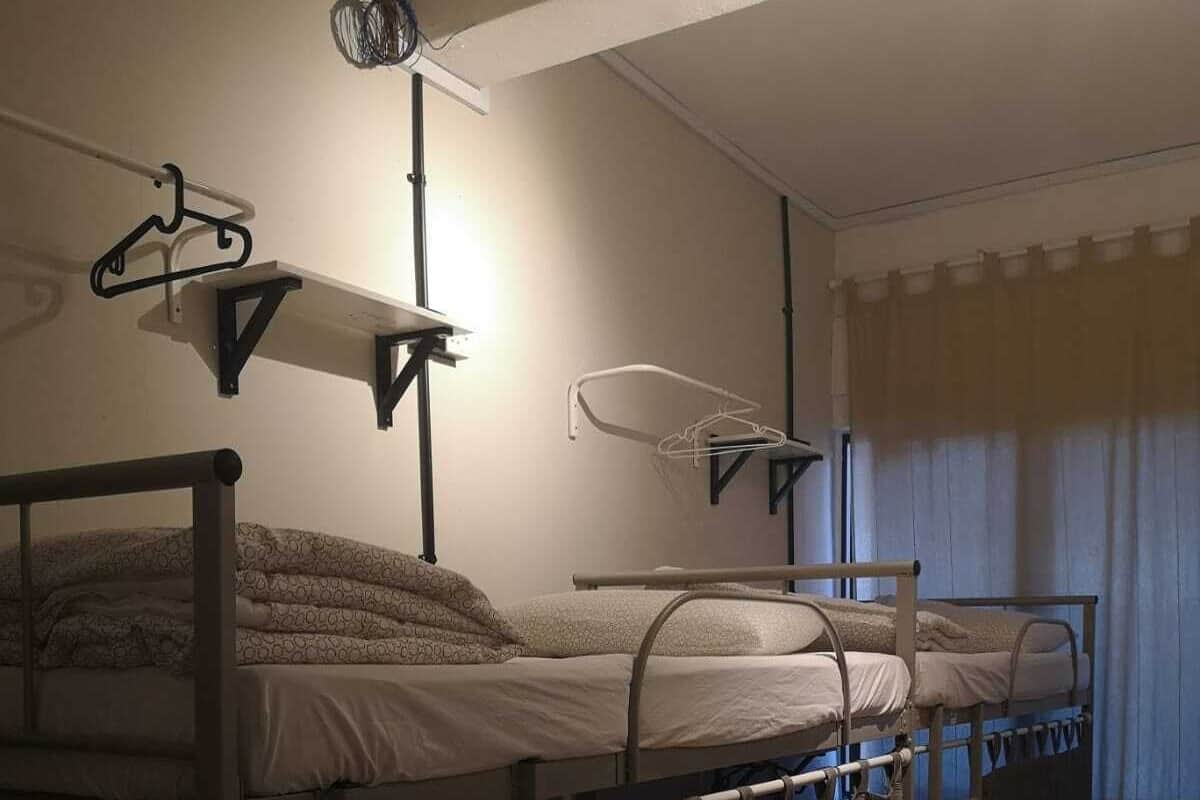 Une chambre de dortoir avec des lits superposés, un luminaire suspendu et un rideau.