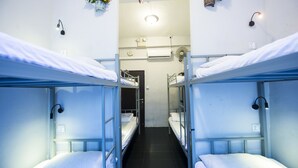 A dormitory room with bunk beds, a small window, and a wall-mounted air conditioner. - Urban Hostel (Singapore)