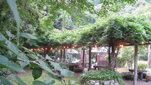 Un jardín con pérgolas de madera, luces colgantes y zonas de estar al aire libre.