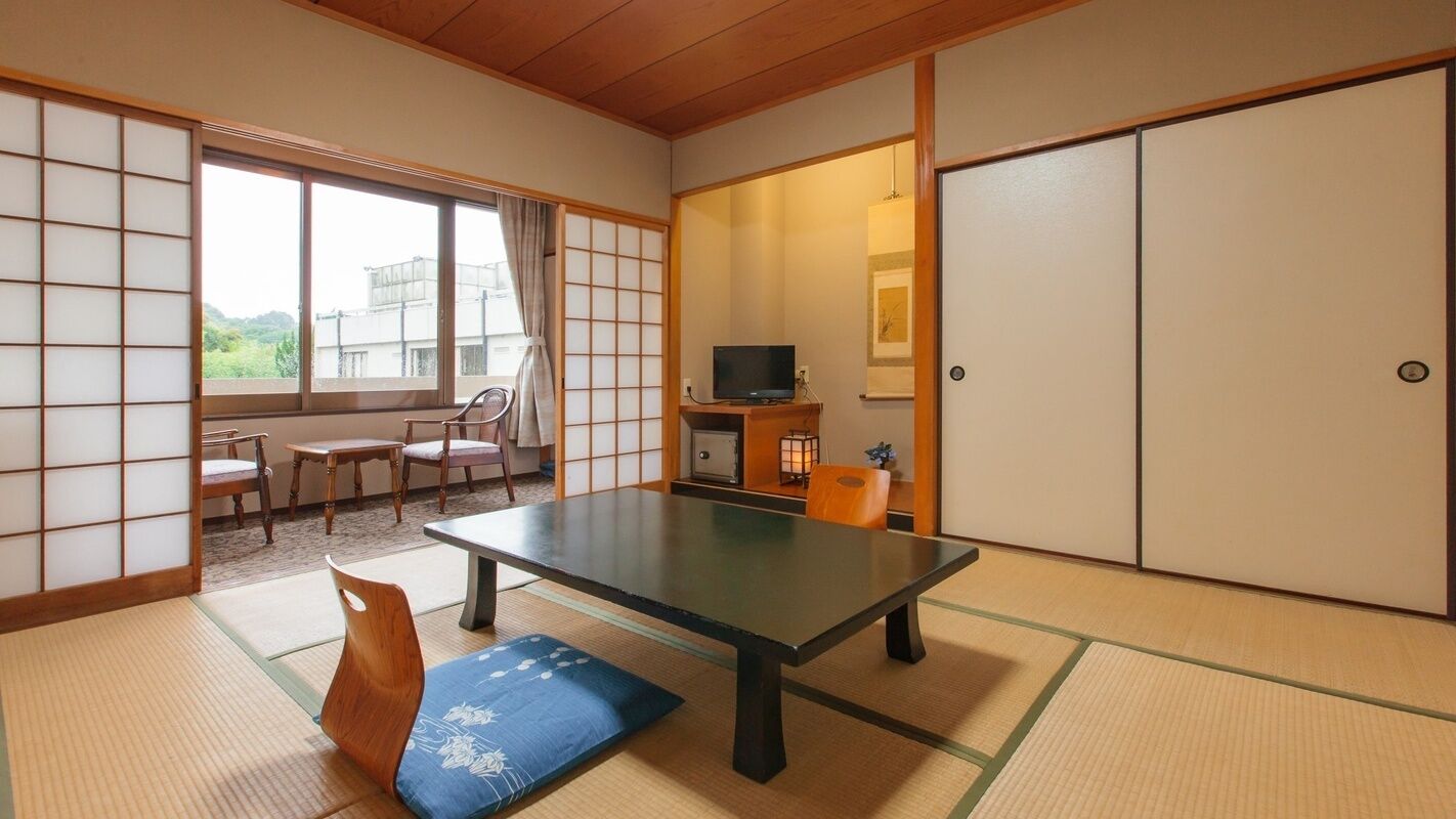 Habitació japonesa tradicional amb fons de tatami, una taula baixa, televisió i portes corredisses.