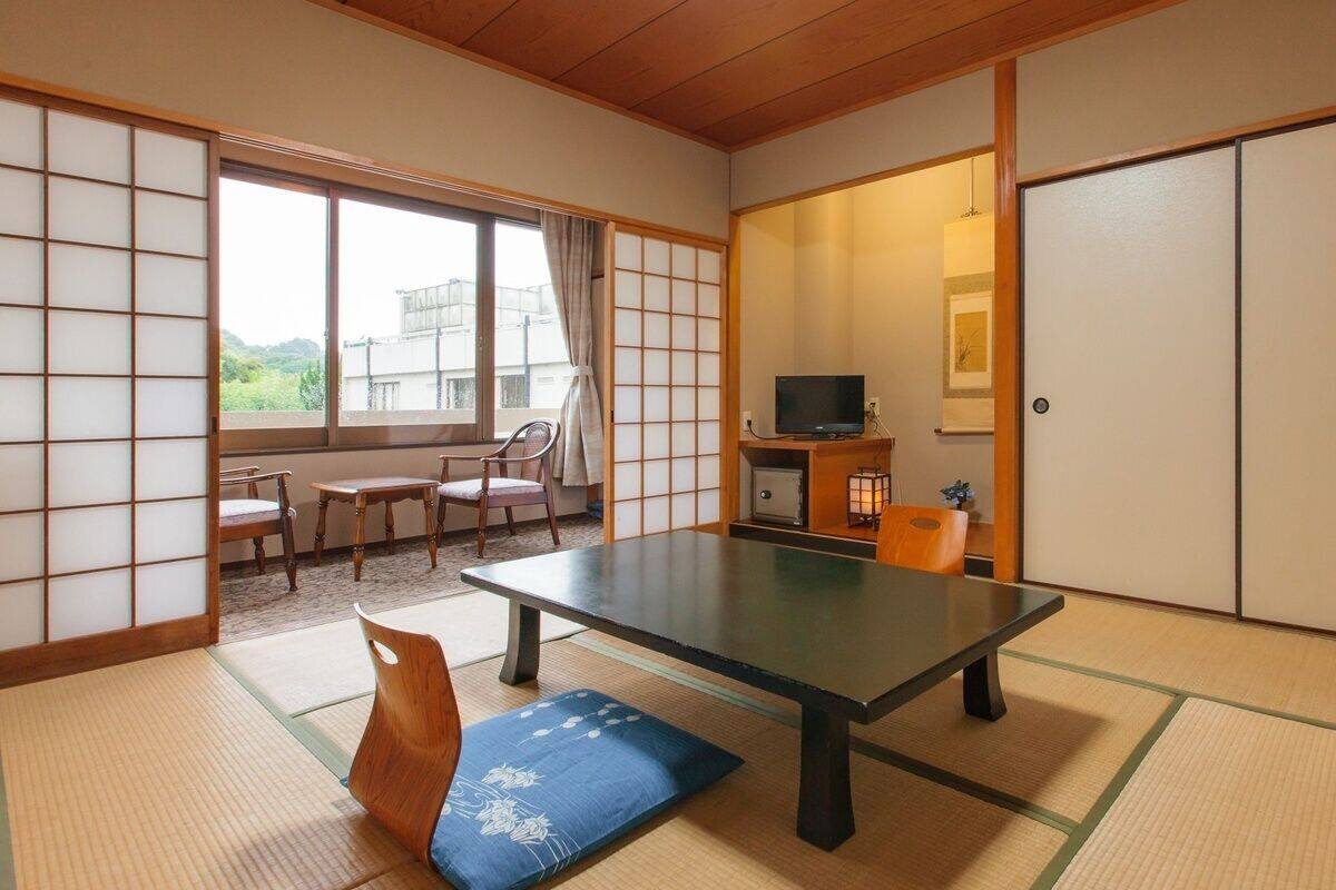 A traditional Japanese room with tatami flooring, a low table, a television, and sliding doors.