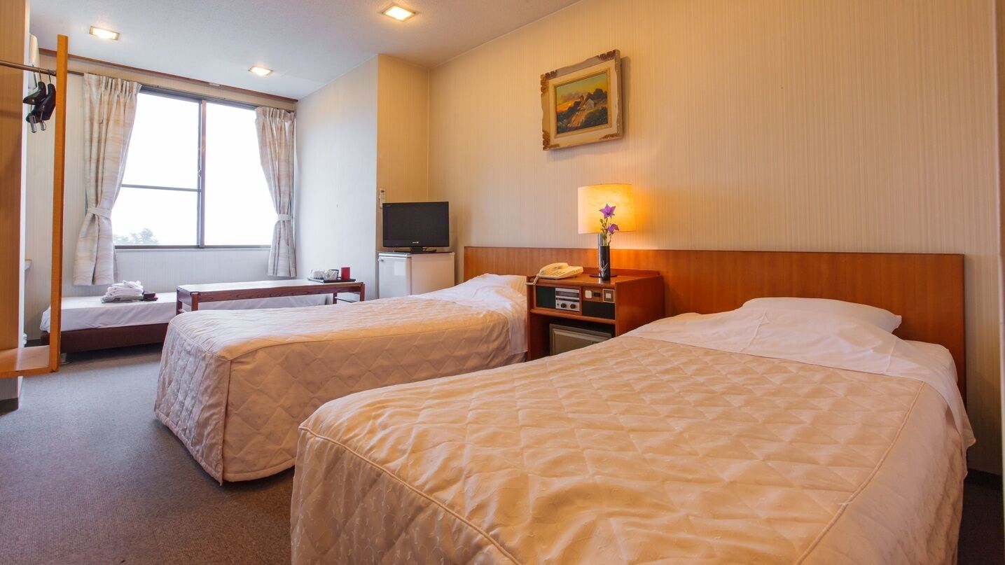 Habitació d'hotel amb dos llits, una televisió, escriptori, làmpada i un quadre a la paret.