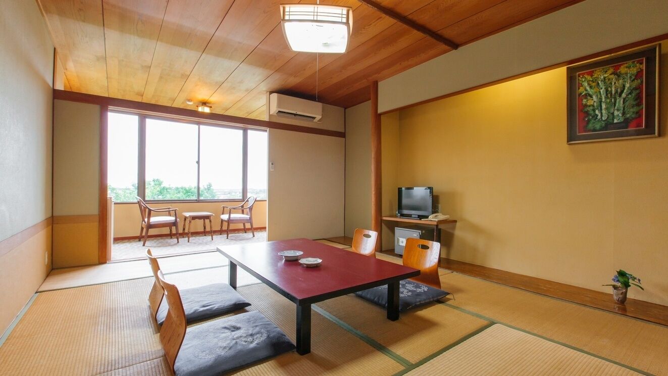 Habitació japonesa tradicional amb tatami, una taula baixa amb coixins, televisió i un quadre a la paret.