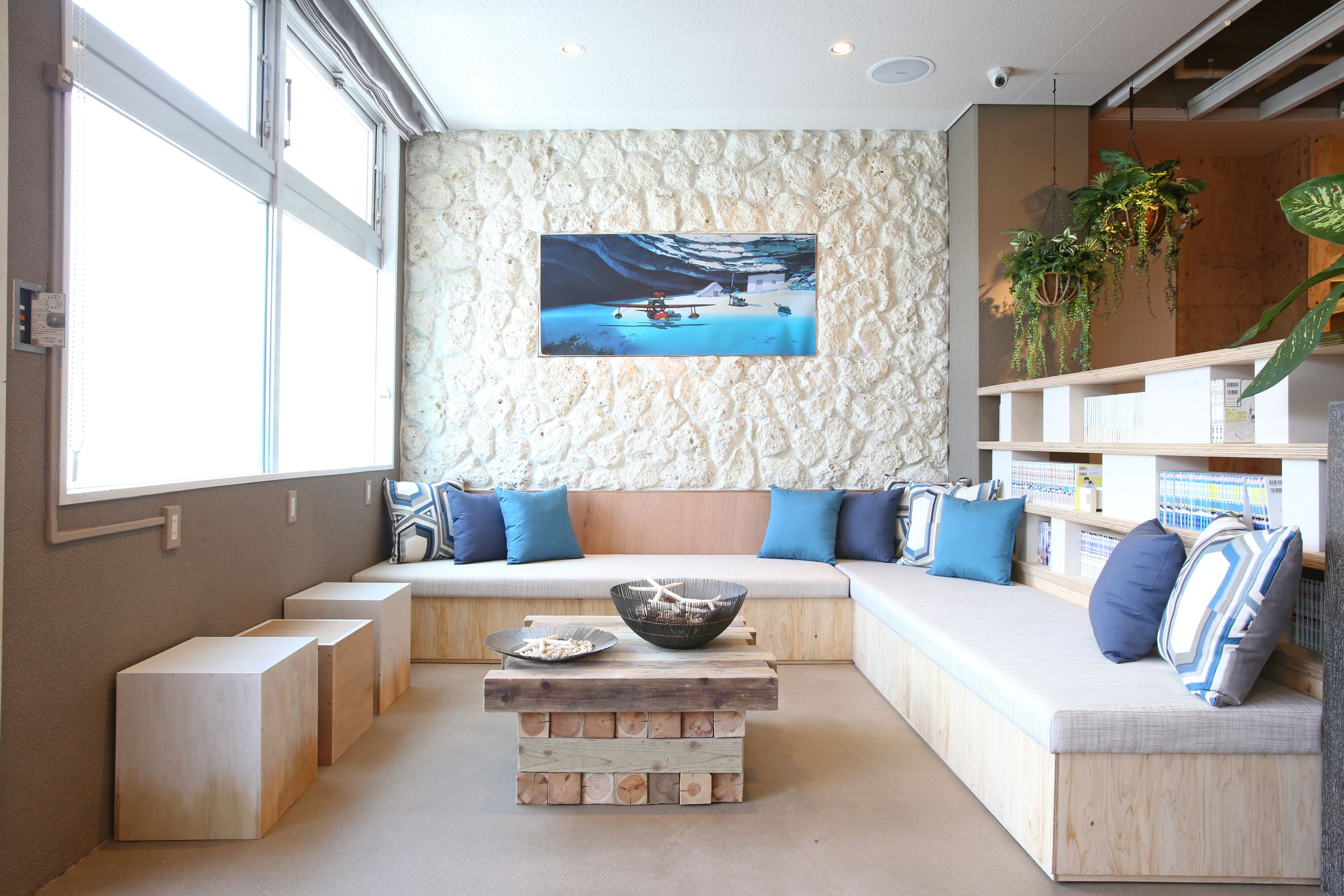A modern living room with a large window, a stone wall, a wooden bench, and a coffee table.