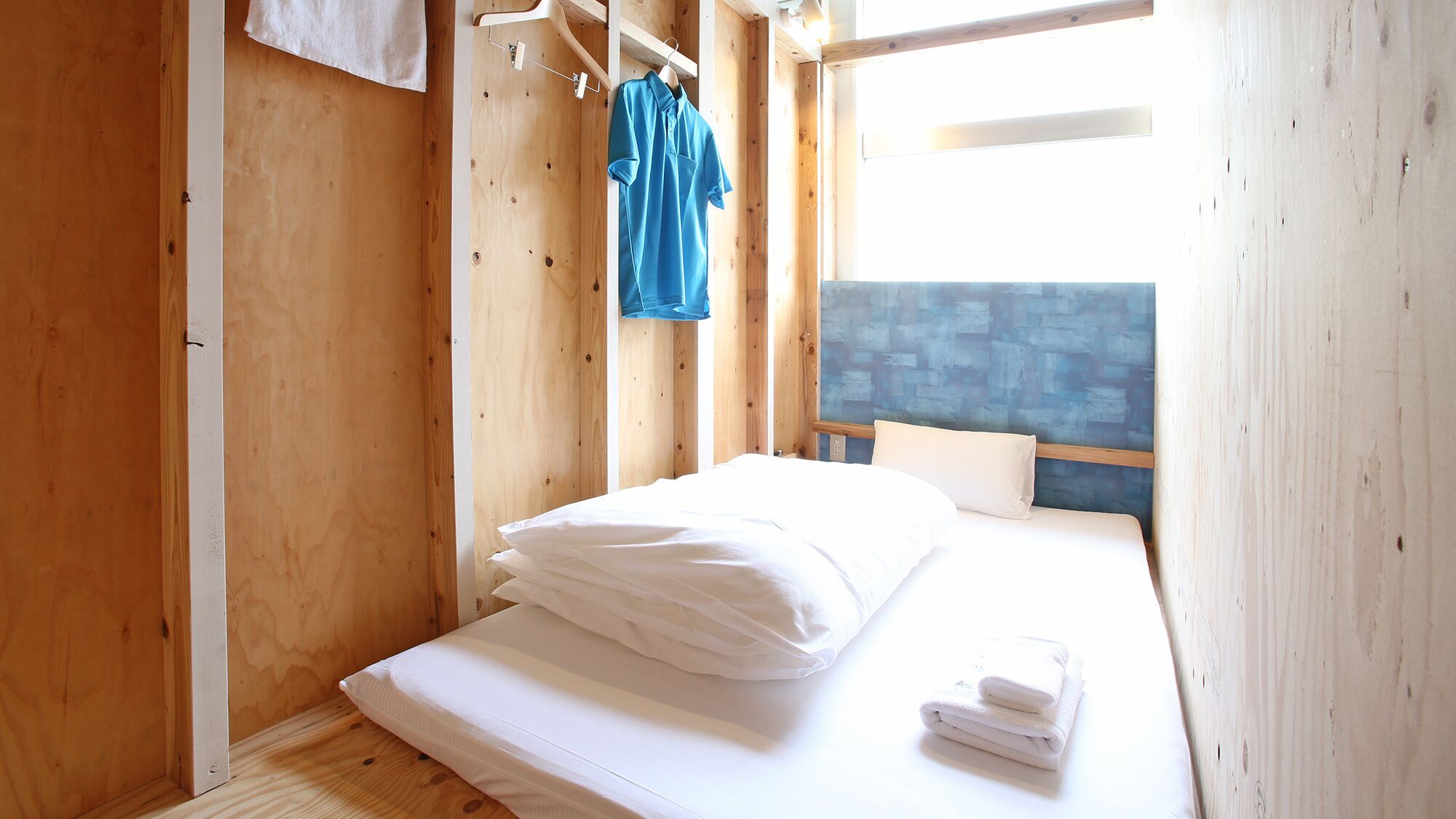 A wooden room with a bed, a hanging towel rack, and a blue towel.