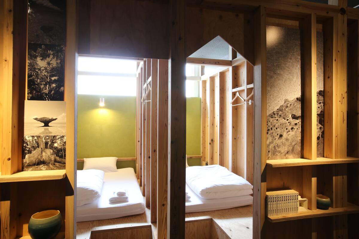 Ein Zimmer mit Holzboden, zwei Betten, einer grünen Wand und einer Steinwand.