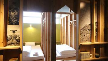 Una habitación de madera con dos camas, una pared verde y una de piedra.
