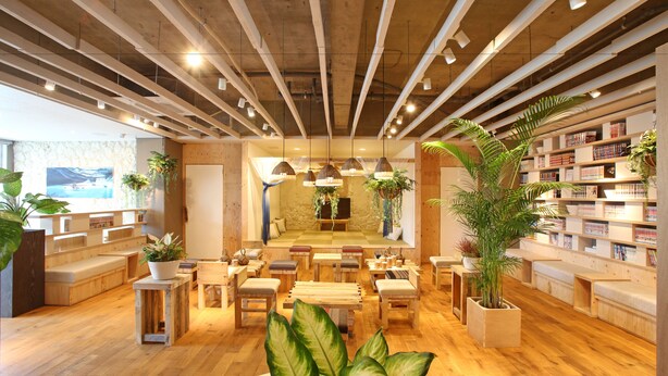 A spacious library with wooden floors, multiple seating areas, and a variety of plants. - Guesthouse Chura Cucule Ishigakijima – Hostel (Ishigaki)
