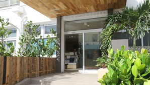A modern building entrance with a wooden fence, a concrete staircase, and lush greenery. - Guesthouse Chura Cucule Ishigakijima – Hostel (Ishigaki)