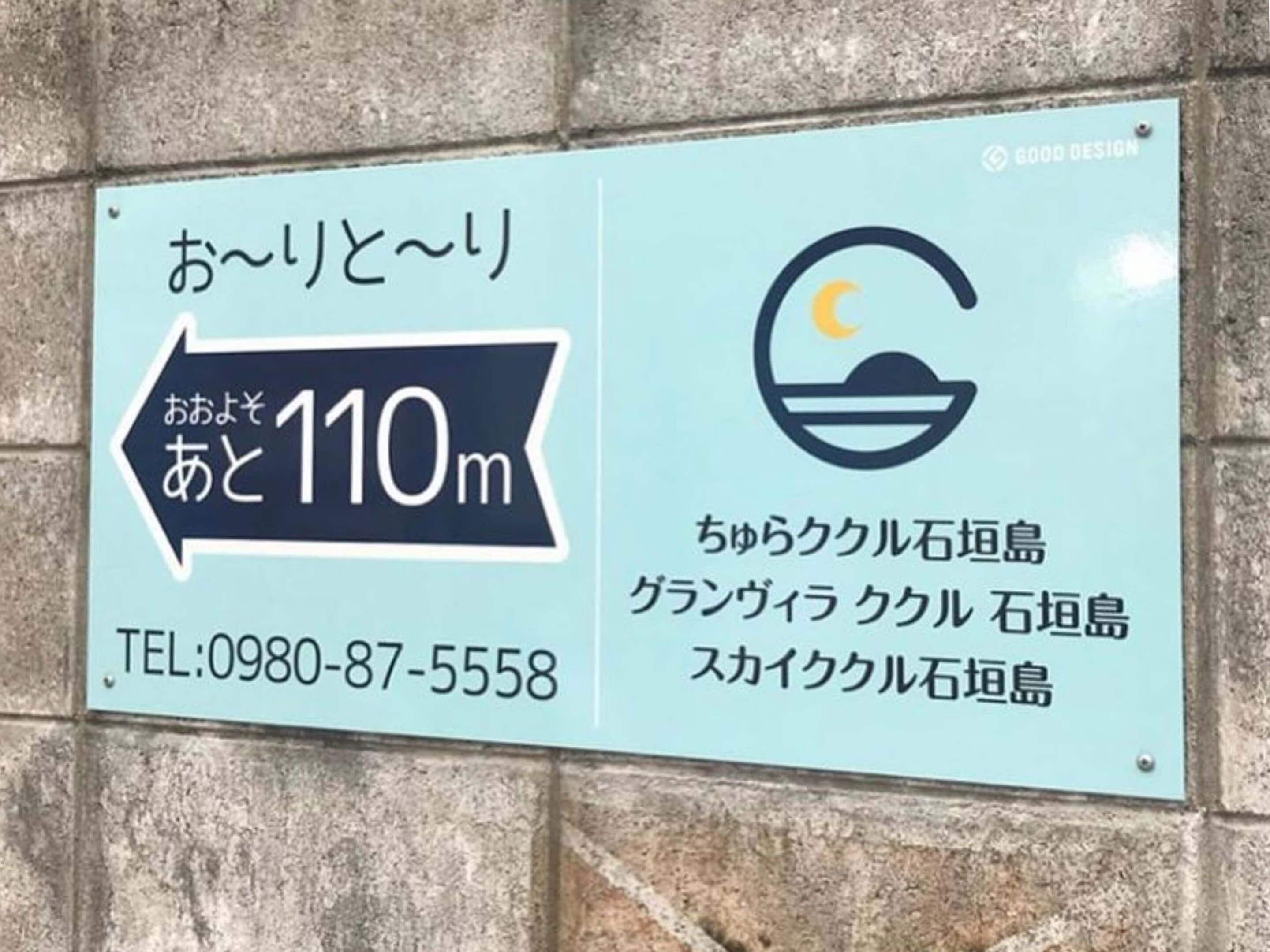 A sign with Japanese text, a directional arrow, and a logo.
