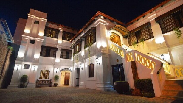 A traditional colonial-style building with a central courtyard, multiple balconies, and a well-lit entrance.