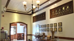 A hallway with wooden flooring, a chandelier, a console table with vases, and framed pictures on the wall.