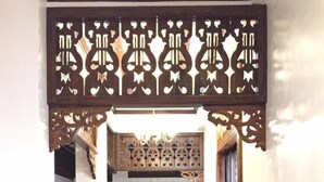 A wooden staircase with intricate carvings and a chandelier, leading to an upper floor.