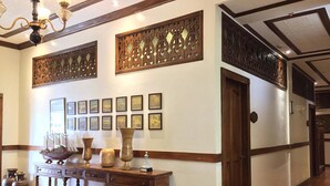 A hallway with wooden paneling, a wooden console table with vases, and framed pictures on the wall.