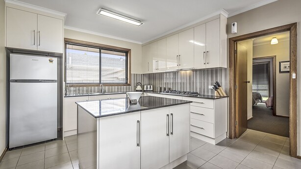A modern kitchen with white cabinetry, a central island, and a built-in stove.
