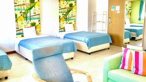 A hotel room with two beds, a green armchair, a wooden chair, and a small table. - Hotel Happy Holiday Ishigakijima (Ishigaki)