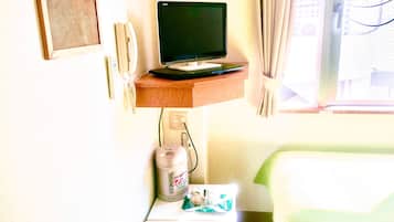 Ein Hotelzimmer mit Fernseher auf einer Holzablage, einem Wasserkocher und einem kleinen Tisch mit Tasse und Untertasse.
