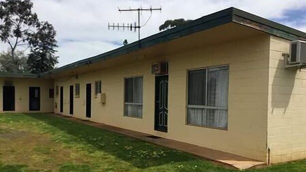 Un motel d’un seul étage, doté d’un toit plat, d’une entrée centrale et d’un petit jardin à l’avant.