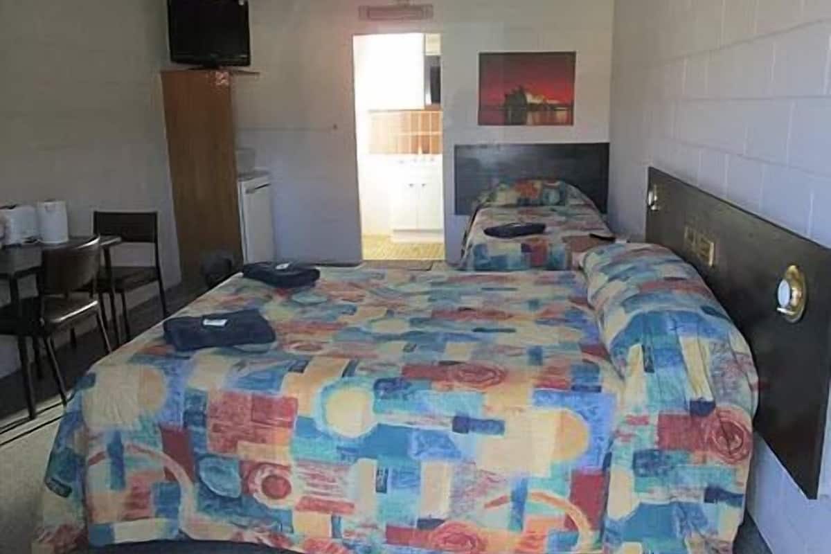 Ein Hotelzimmer mit Bett, Fernseher, Schreibtisch und Stuhl.