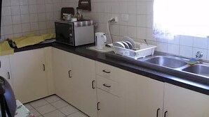 Une cuisine avec des meubles blancs, un plan de travail noir, un grille-pain et un égouttoir à vaisselle.