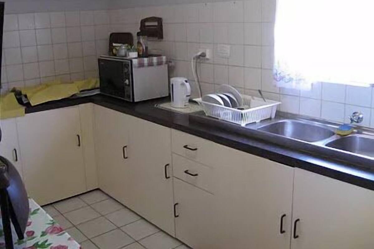 Eine Küche mit weißen Schränken, einer schwarzen Arbeitsplatte, einem Toaster und einem Geschirrgestell.