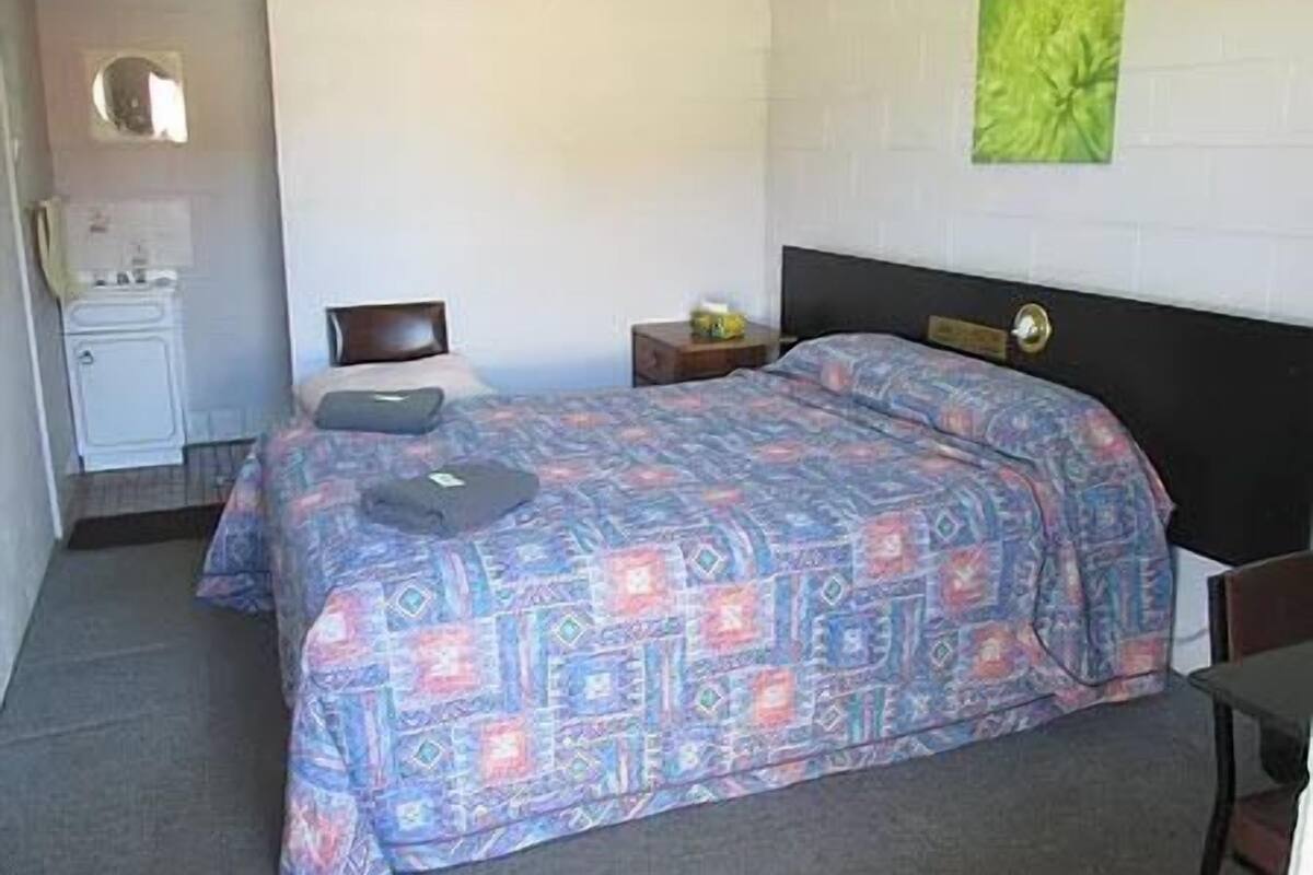 Ein Schlafzimmer mit Bett, Nachttisch, Kommode und einer grünen Wanddekoration.