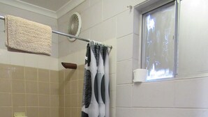 Une salle de bain avec une douche, des toilettes et un porte-serviettes.