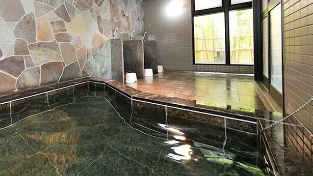 A stone-walled bathroom with a glass-enclosed hot tub area. - Hotel Shinsuien (Nagoya)