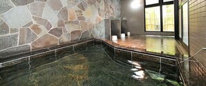 A stone-walled bathroom with a glass-enclosed hot tub area. - Hotel Shinsuien (Nagoya)