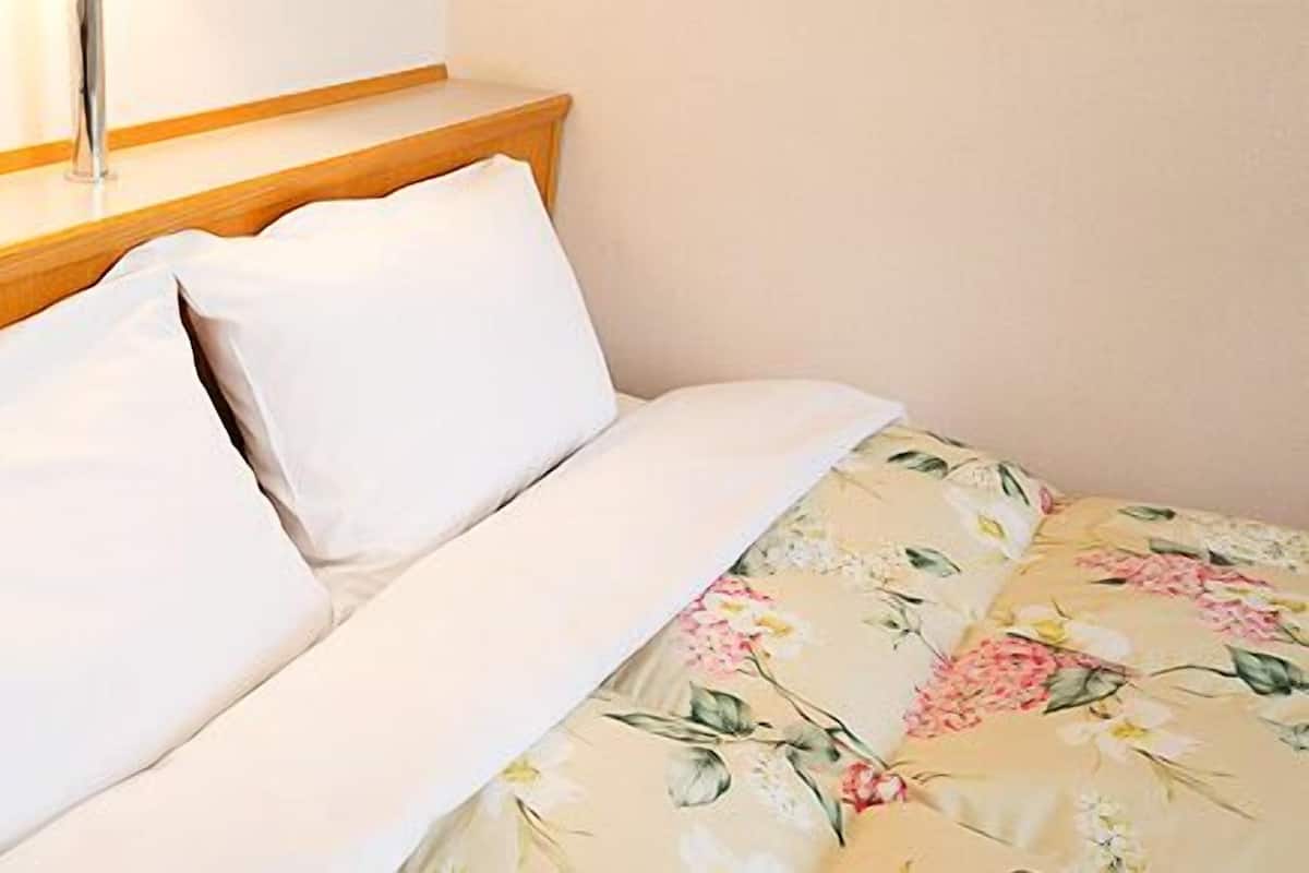 A hotel room with a wooden headboard, a white telephone, and a floral bedspread.