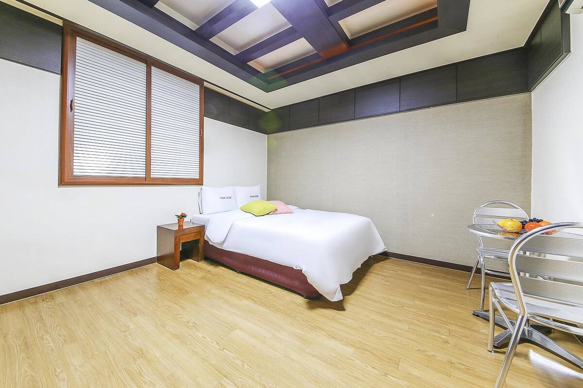 A bedroom with a bed, bedside table, and a small table with fruits.