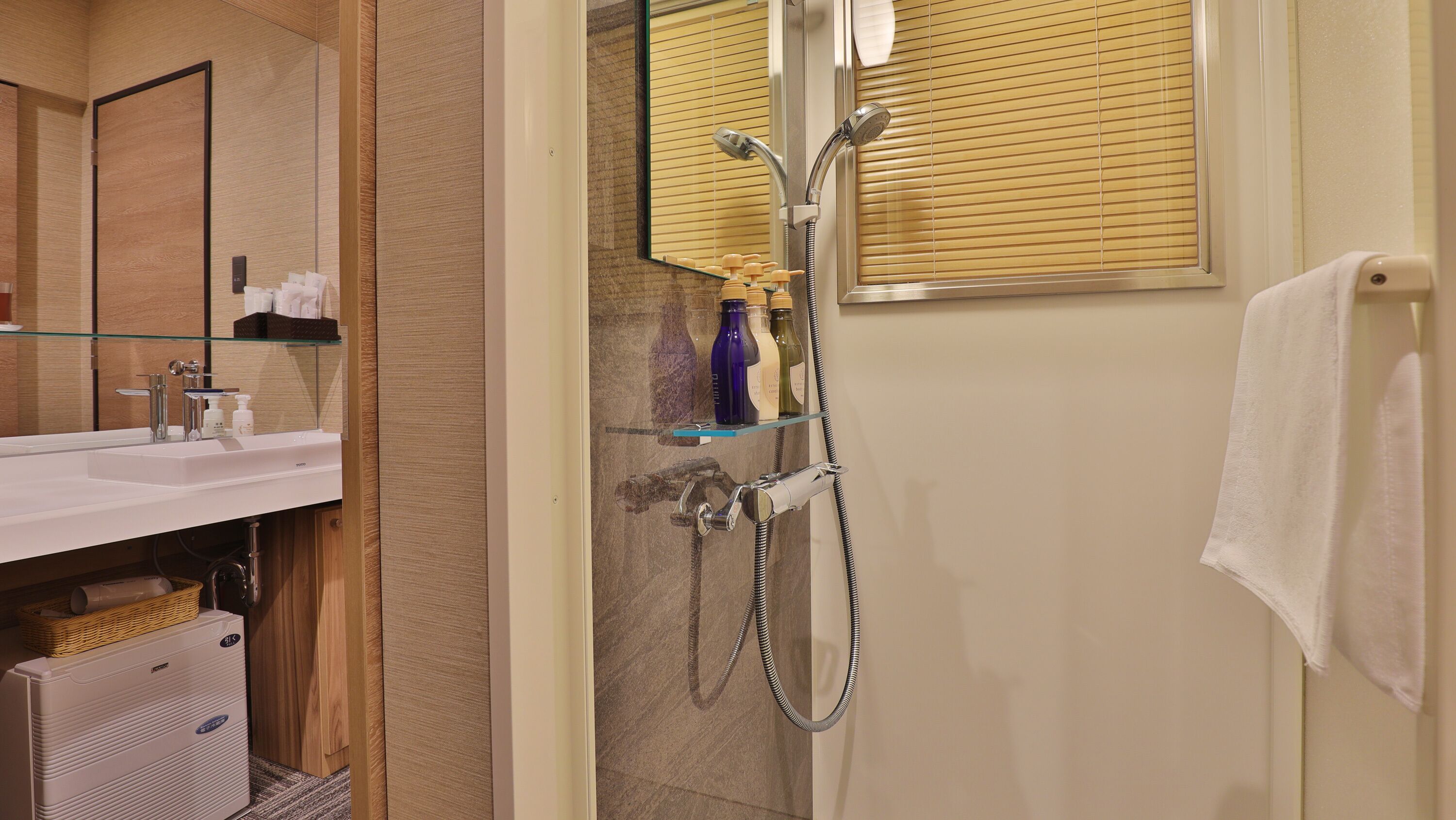 Un baño moderno con cabina de ducha de vidrio, lavamanos blanco y espejo.