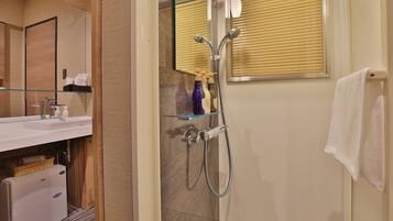 Un baño moderno con cabina de ducha de vidrio, lavamanos blanco y espejo.