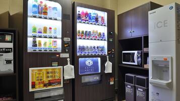 Máquina expendedora con bebidas y aperitivos, microondas y refrigerador con la etiqueta 'ICE'.