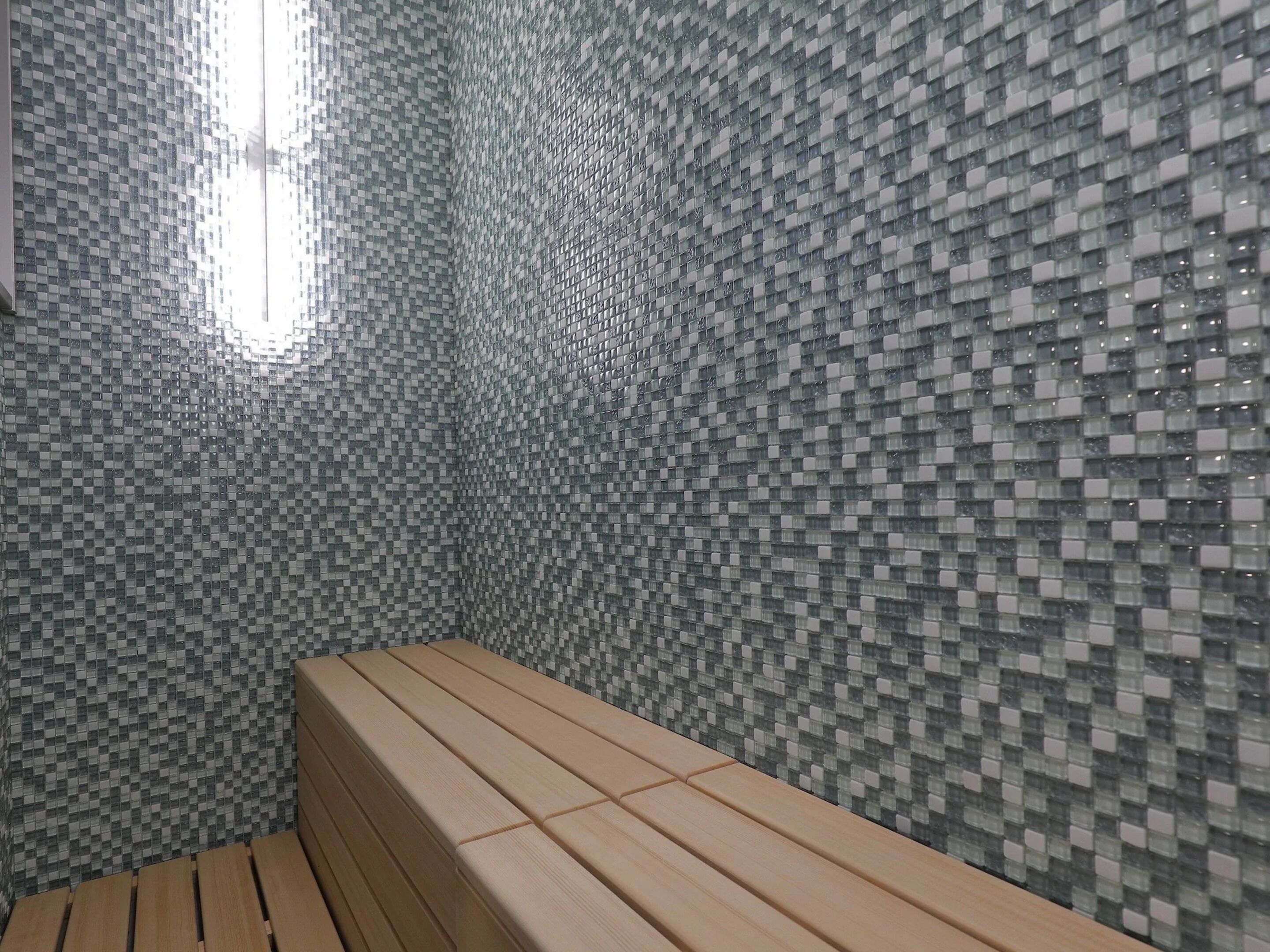 Une salle de bain avec un mur carrelé et un banc en bois.