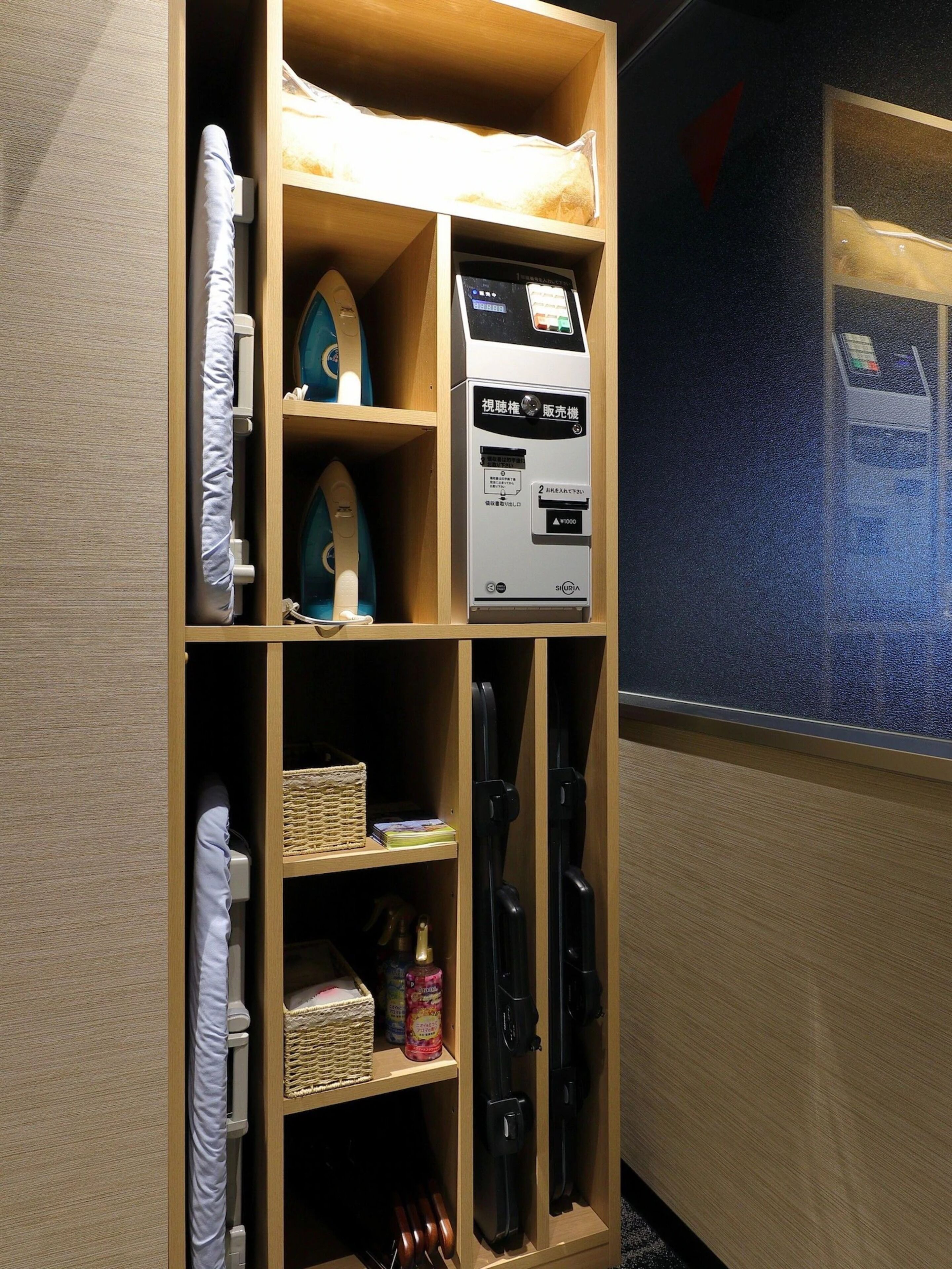 A storage unit with shelves containing various items including a vacuum cleaner, a small appliance, and personal items.