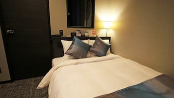 A hotel room with a bed, a nightstand, a lamp, and a door.