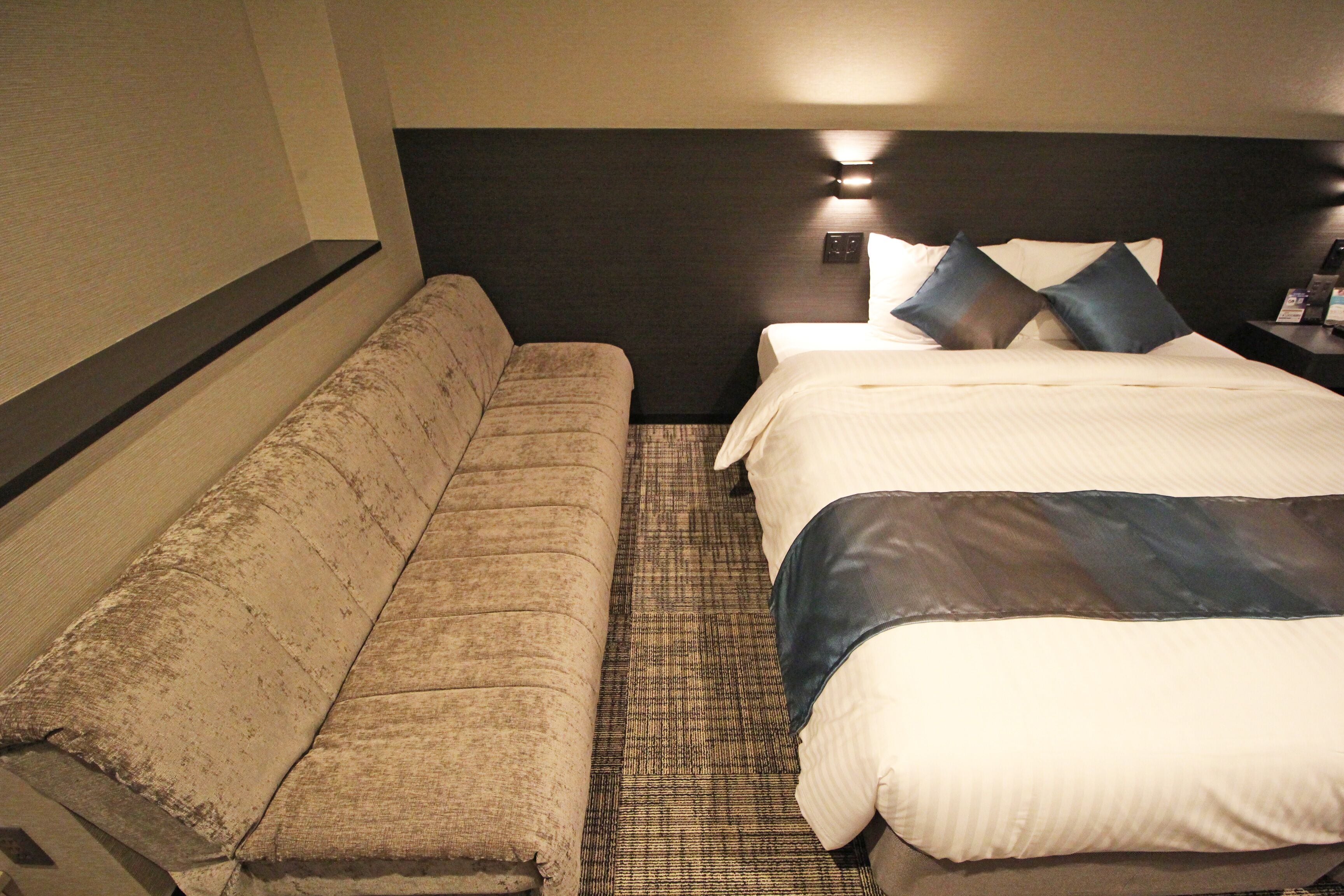A hotel room with a bed, a sofa, and a nightstand.