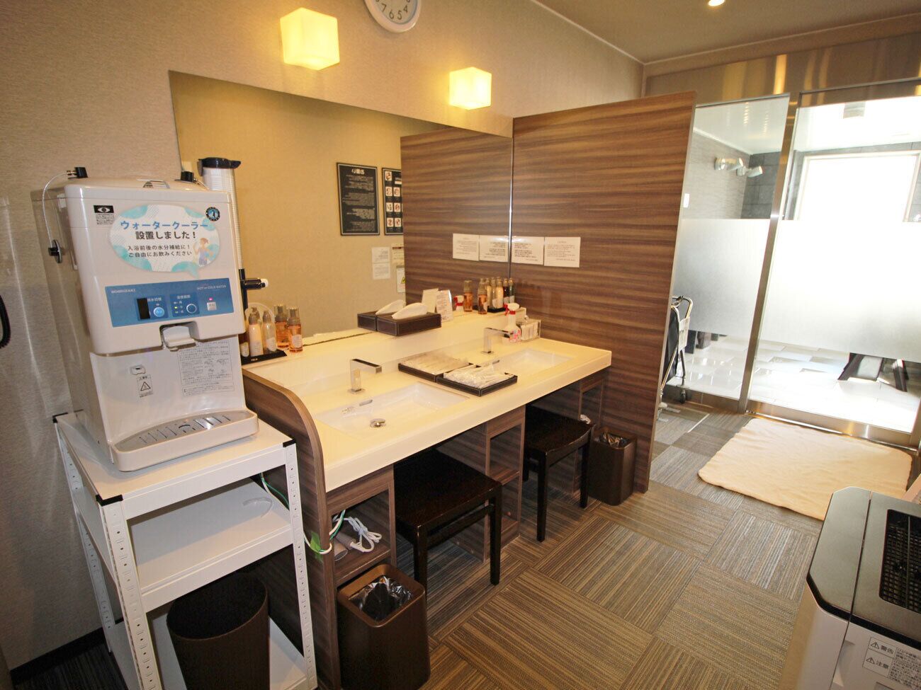 A hotel bathroom with a sink, mirror, and a water dispenser.