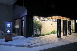 Fachada de hotel de diseño moderno, con un frente geométrico y una entrada acogedora con puertas de vidrio.